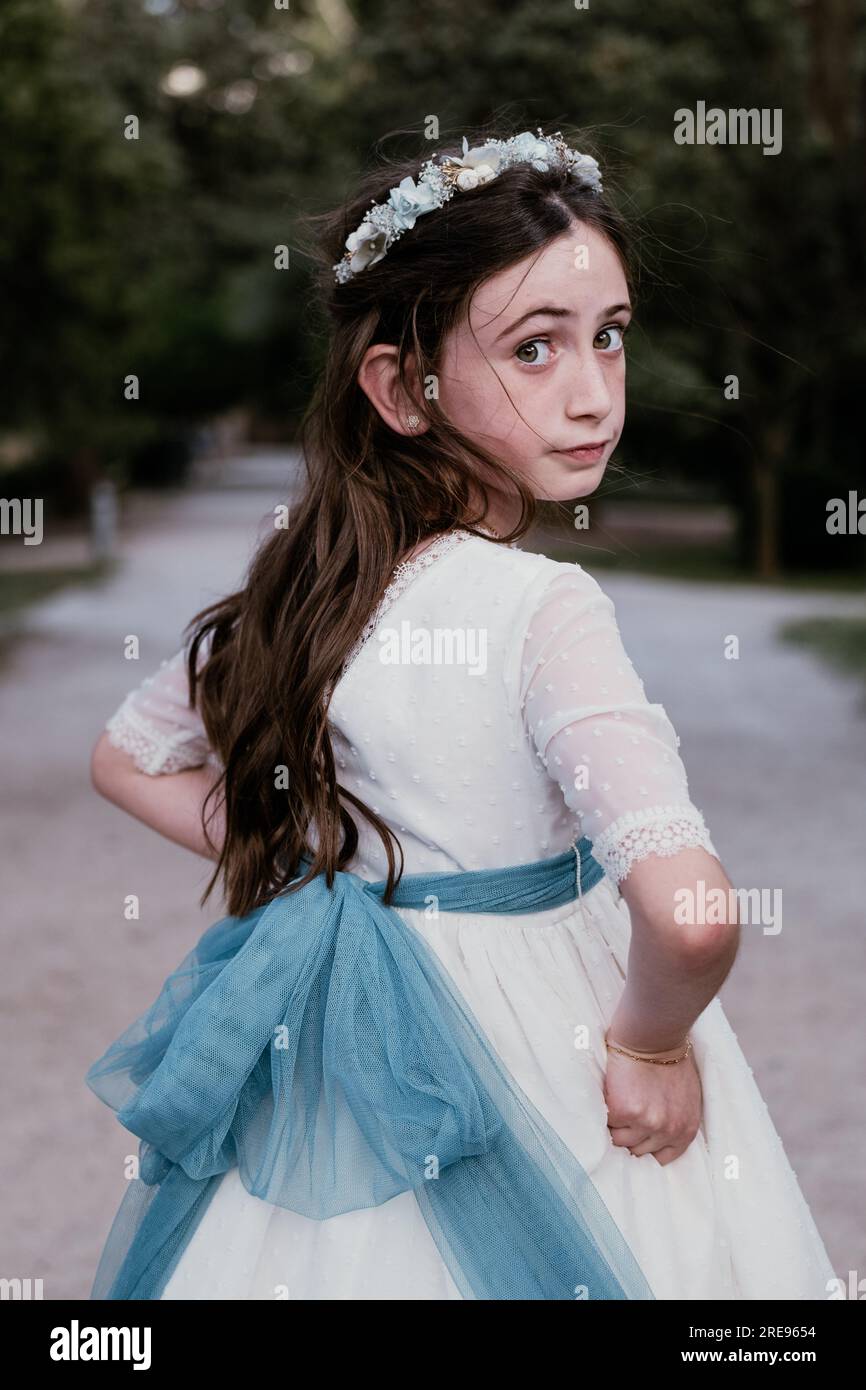 Side view of calm teen girl in elegant white fancy dress standing in ...