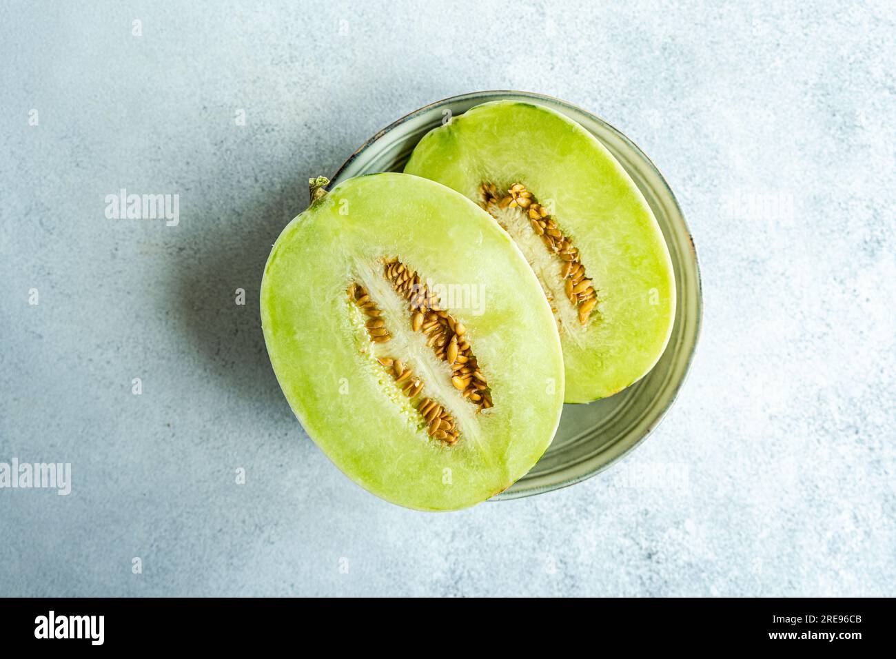 Top view melon split in half placed in a bowl on concrete background Stock Photo