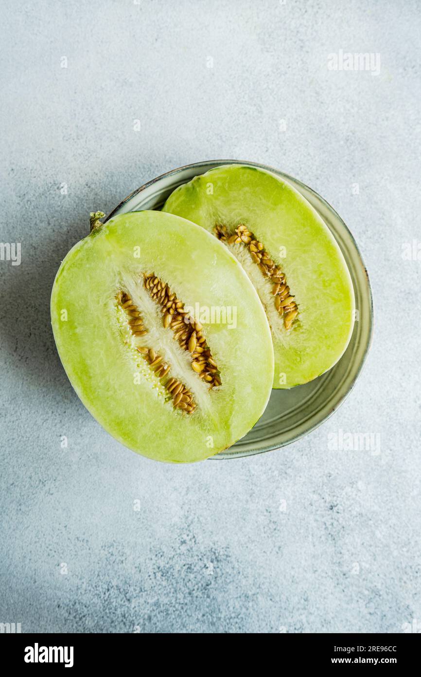 Top view melon split in half placed in a bowl on concrete background Stock Photo