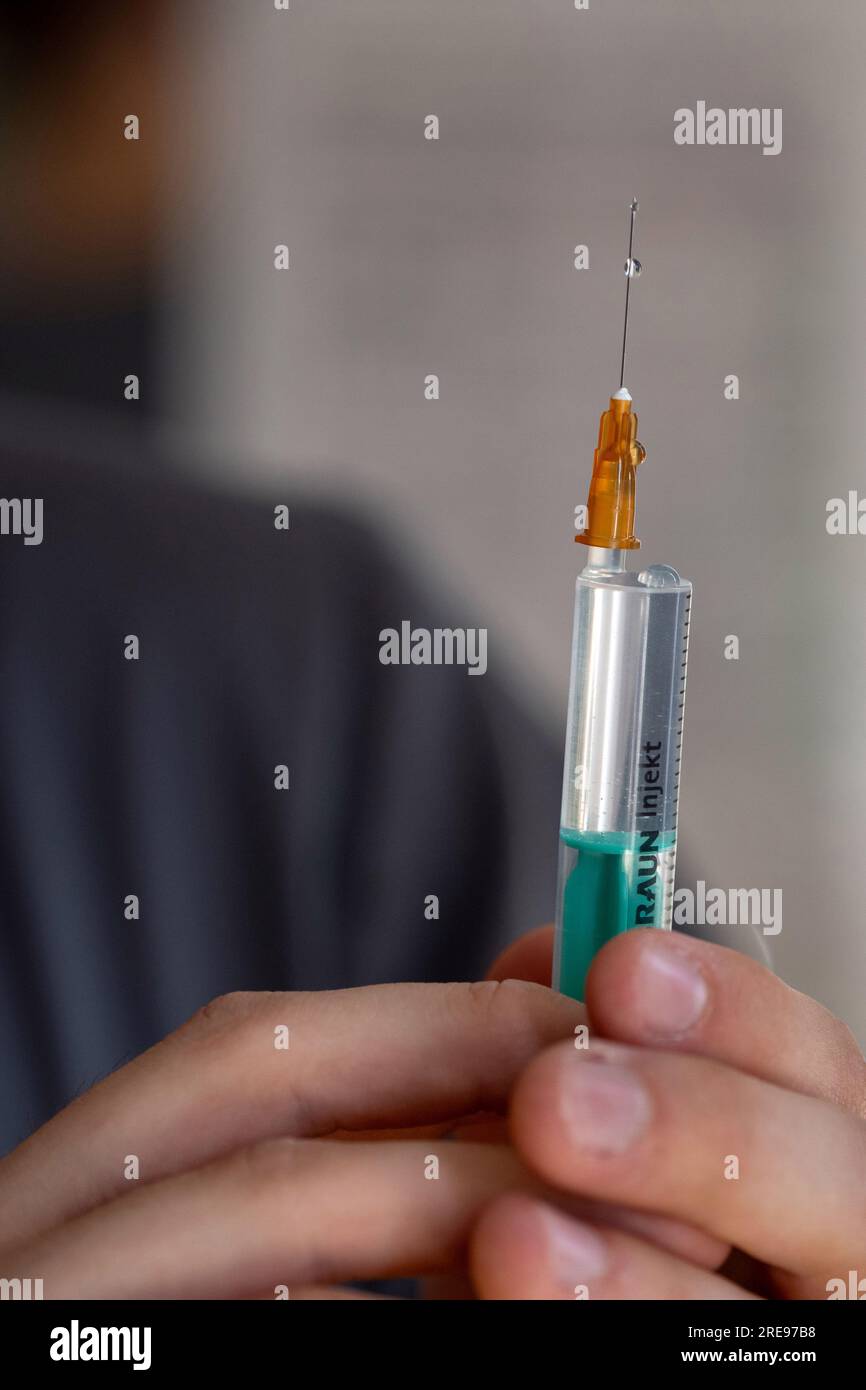 Coburg, Germany. 23rd July, 2023. A nursing student holds a syringe in his hand, a drop of saline runs along the needle. This week, the first graduates in generalist nursing in Bavaria will receive their graduation certificates. Credit: Pia Bayer/dpa/Alamy Live News Stock Photo