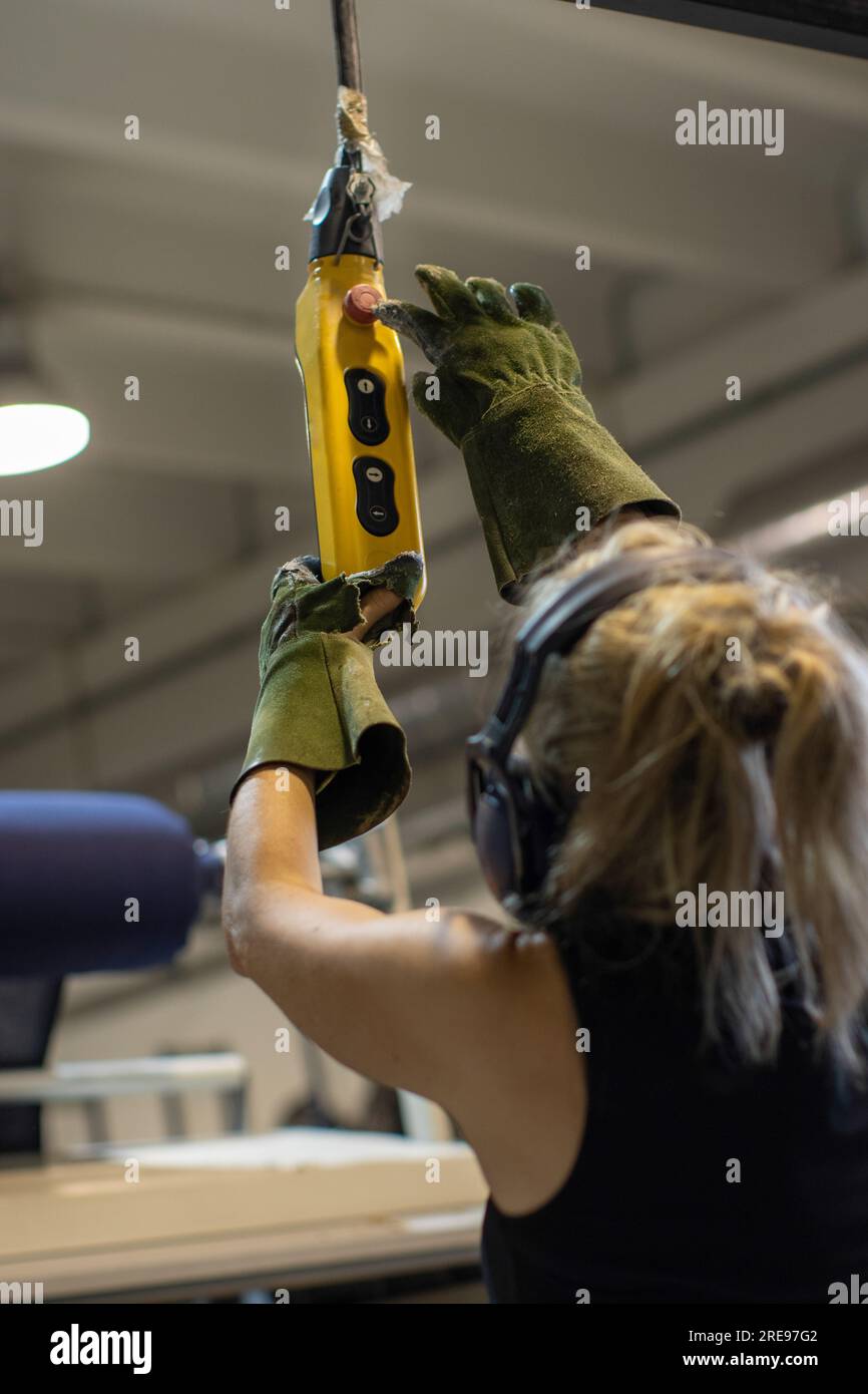 Back view of anonymous female worker in protective earmuffs and gloves ...