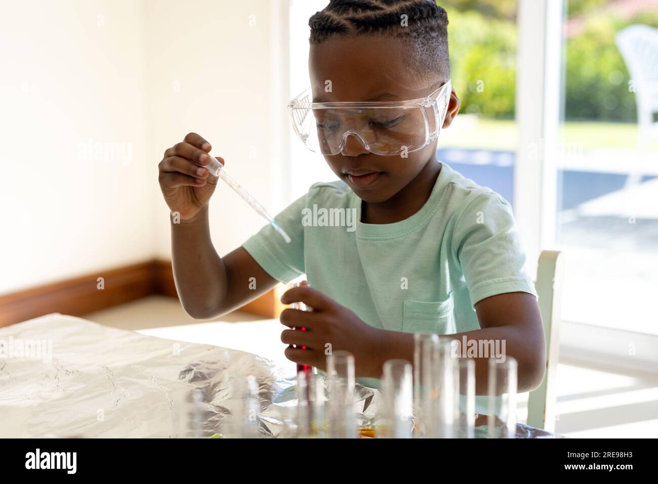 Happy african american boy doing chemistry experiments at home in sunny living room Stock Photo