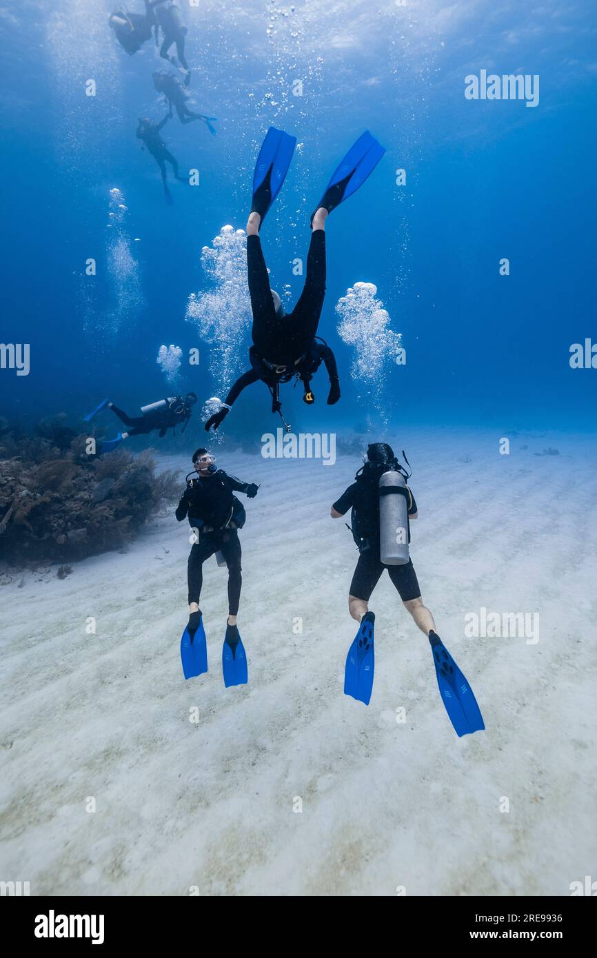 Scuba divers swimming underwater with bubbles while exploring deep