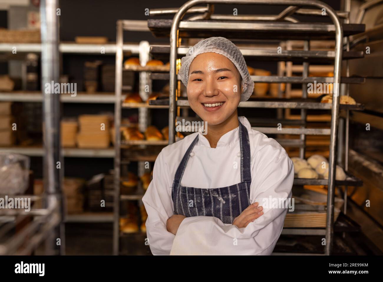 https://c8.alamy.com/comp/2RE99KM/portrait-of-happy-asian-female-baker-in-bakery-kitchen-wearing-apron-with-arms-crossed-2RE99KM.jpg