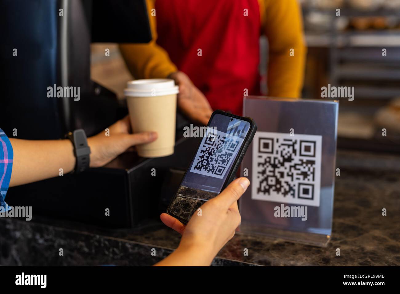 Diverse male bakery worker and customer scanning qr code with