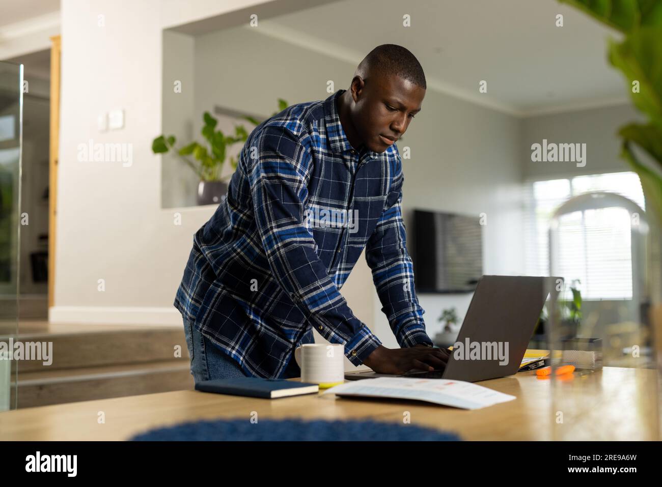 African american man standing at table using laptop at home Stock Photo