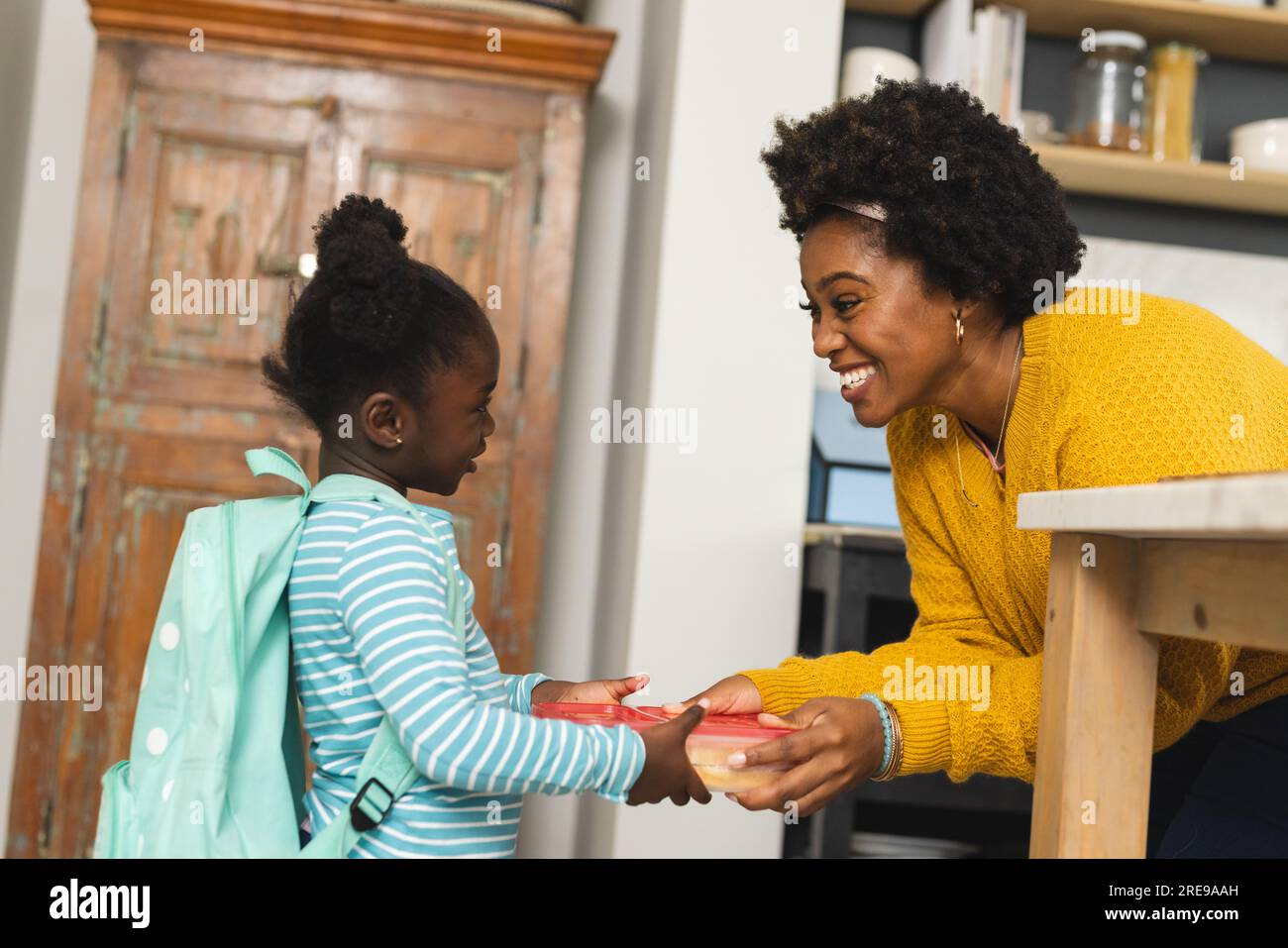 Happy african american mother and daughter preparing lunch for school in kitchen at home Stock Photo