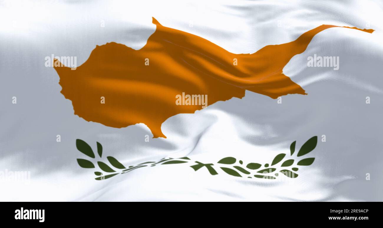 Close-up of Cyprus national flag waving in the wind on a clear day. White with a copper-orange island silhouette and two green olive branches below it Stock Photo