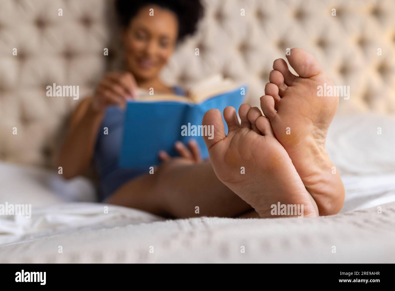Close up of woman female feet in pink socks on a bed in bedroom relaxing in  the evening Stock Photo