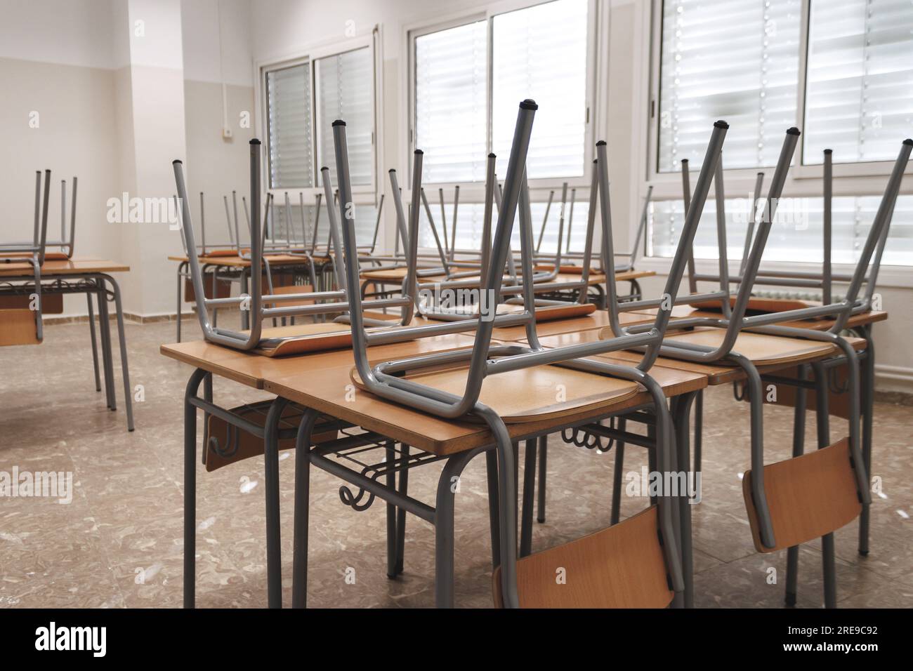 Closeup of similar upside down chairs placed on wooden table in light classroom in school after classes Stock Photo