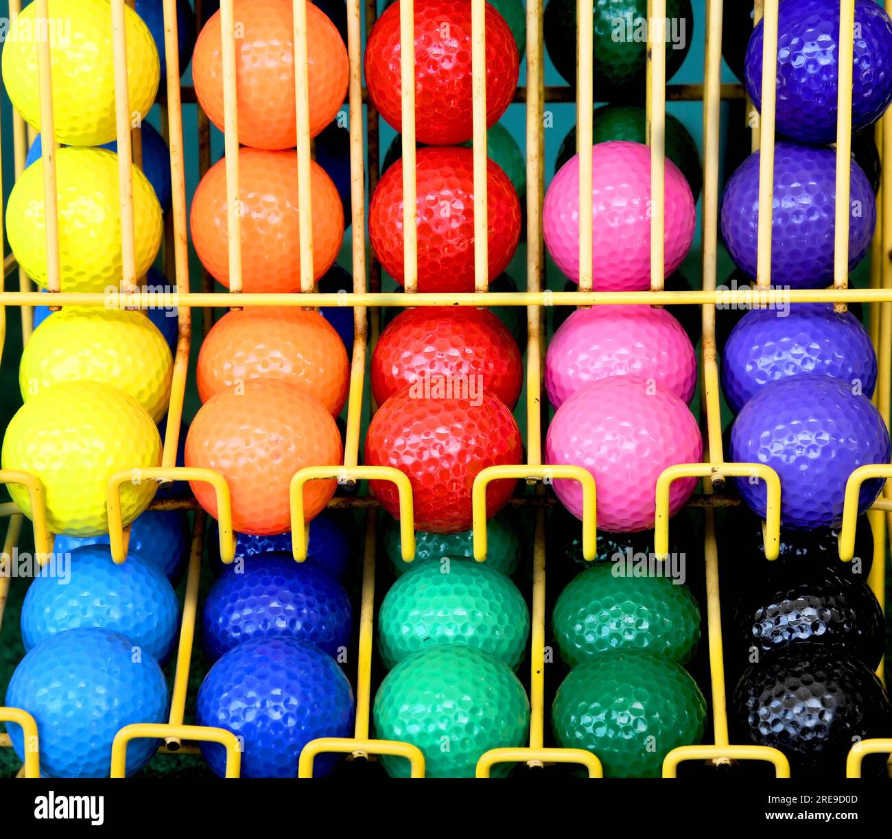 Yellow metal rack holds a group of put-put golf balls in a multitude of ...