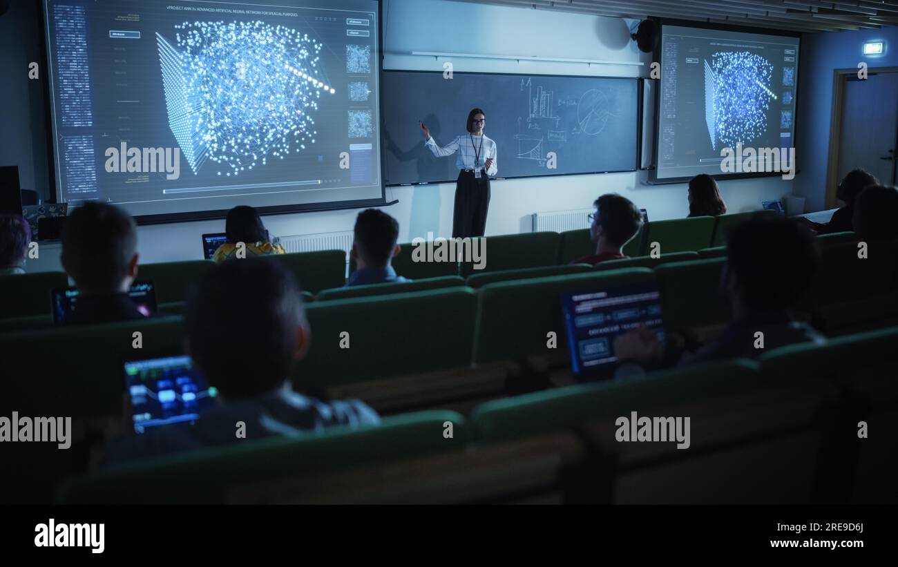 Young Female Teacher Giving a Data Science Lecture to Diverse Multiethnic Group of Female and Male Students in Dark College Room. Projecting Slideshow Stock Photo