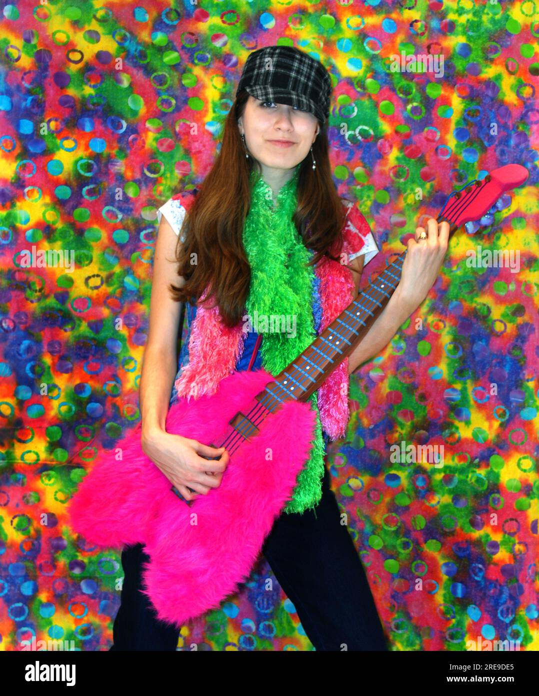 Female teen holds a stuffed, furry, pretend guitar and grooves to the