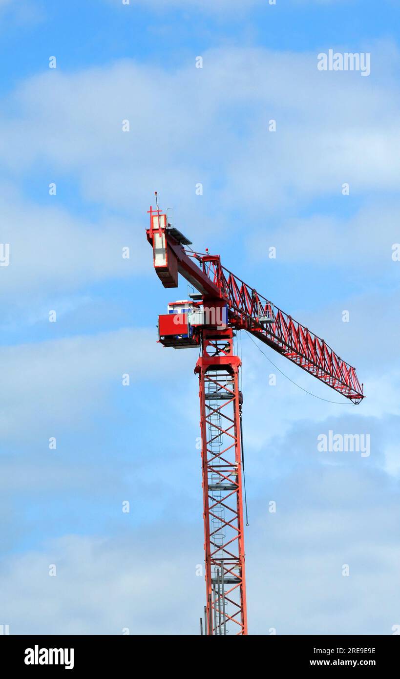 Large red crane hangs over downtown Madison, Wisconsin.  Blue sky and clouds frame it. Stock Photo