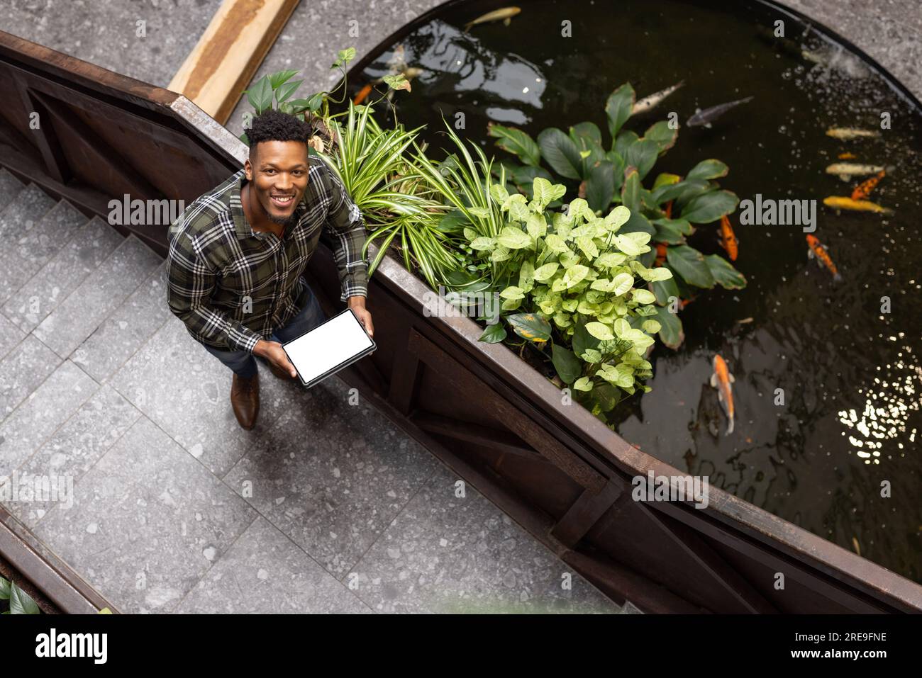 Overhead view of happy african american man holding a tablet with copy space on the stairs at office Stock Photo