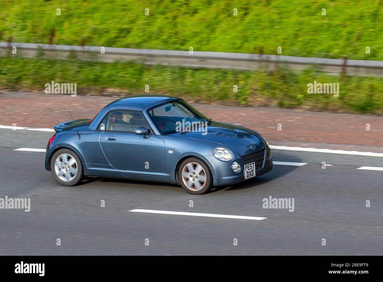 2007 Blue Grey Daihatsu Copen DVVT Car Roadster Petrol 1298 cc,  funky little convertible, 2-door kei car with a metal folding roof, travelling on the M6 motorway in Greater Manchester, UK Stock Photo