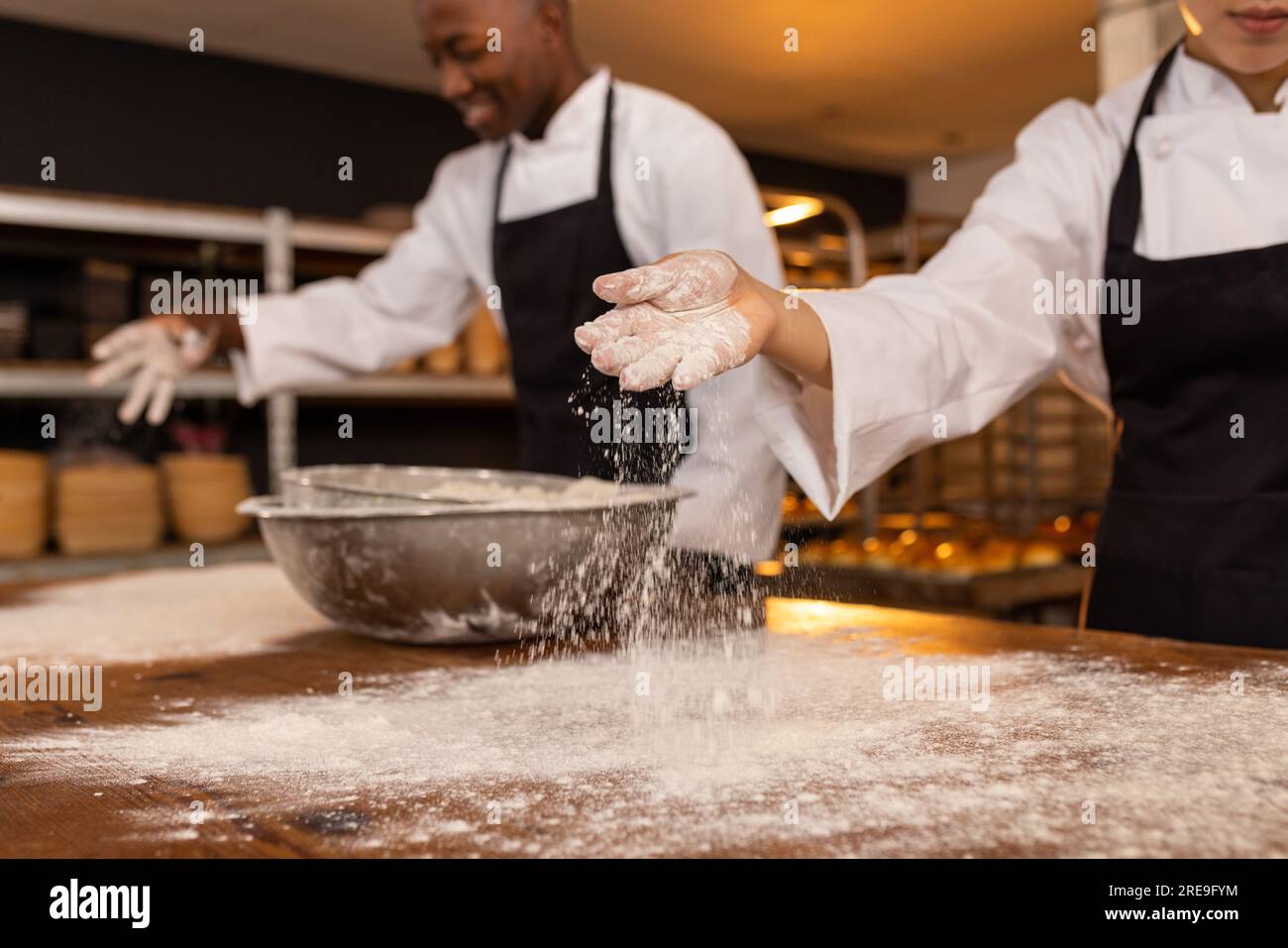 Happy diverse bakers working in bakery kitchen, pouring flour and