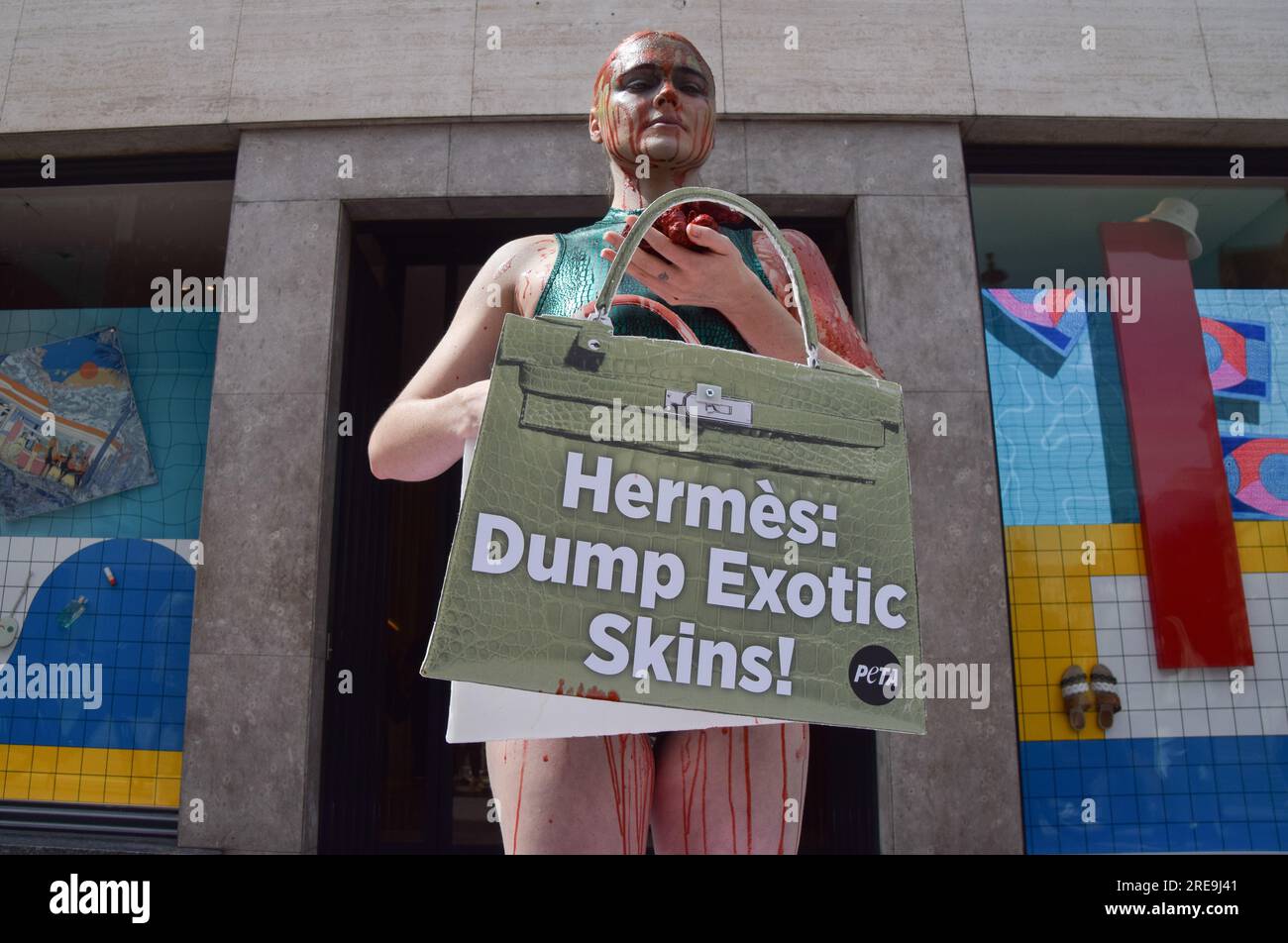 London UK. 26th July 2023. Vegan activist Tash Peterson covered in fake blood holds a mock Hermes bag and fake guts during the protest. PETA People for the Ethical Treatment of Animals