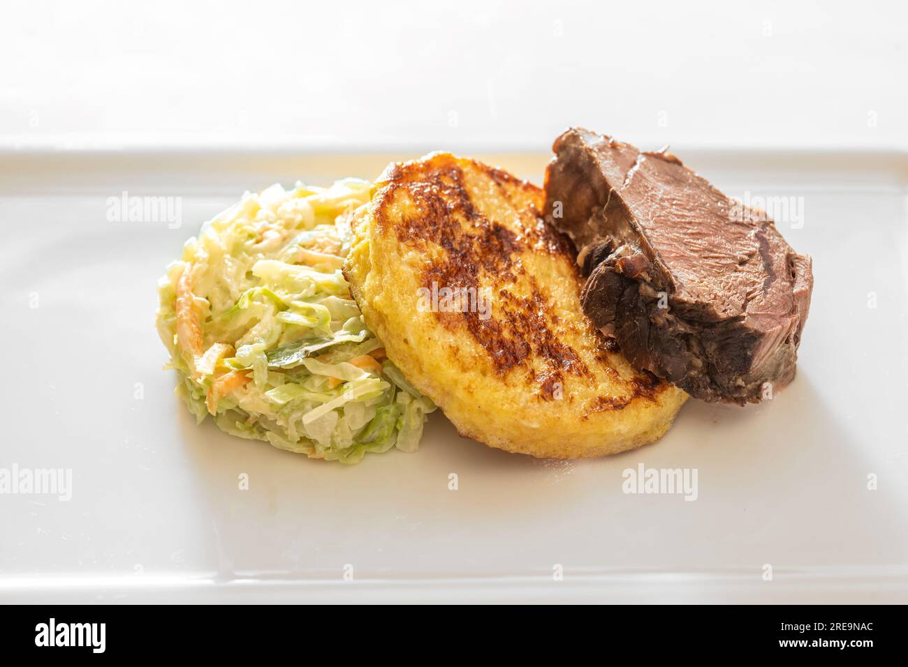 Roast deer, flat bread dumpling and round shaped vegetables, gourmet dish on a white plate, copy space, selected focus, narrow depth of field Stock Photo