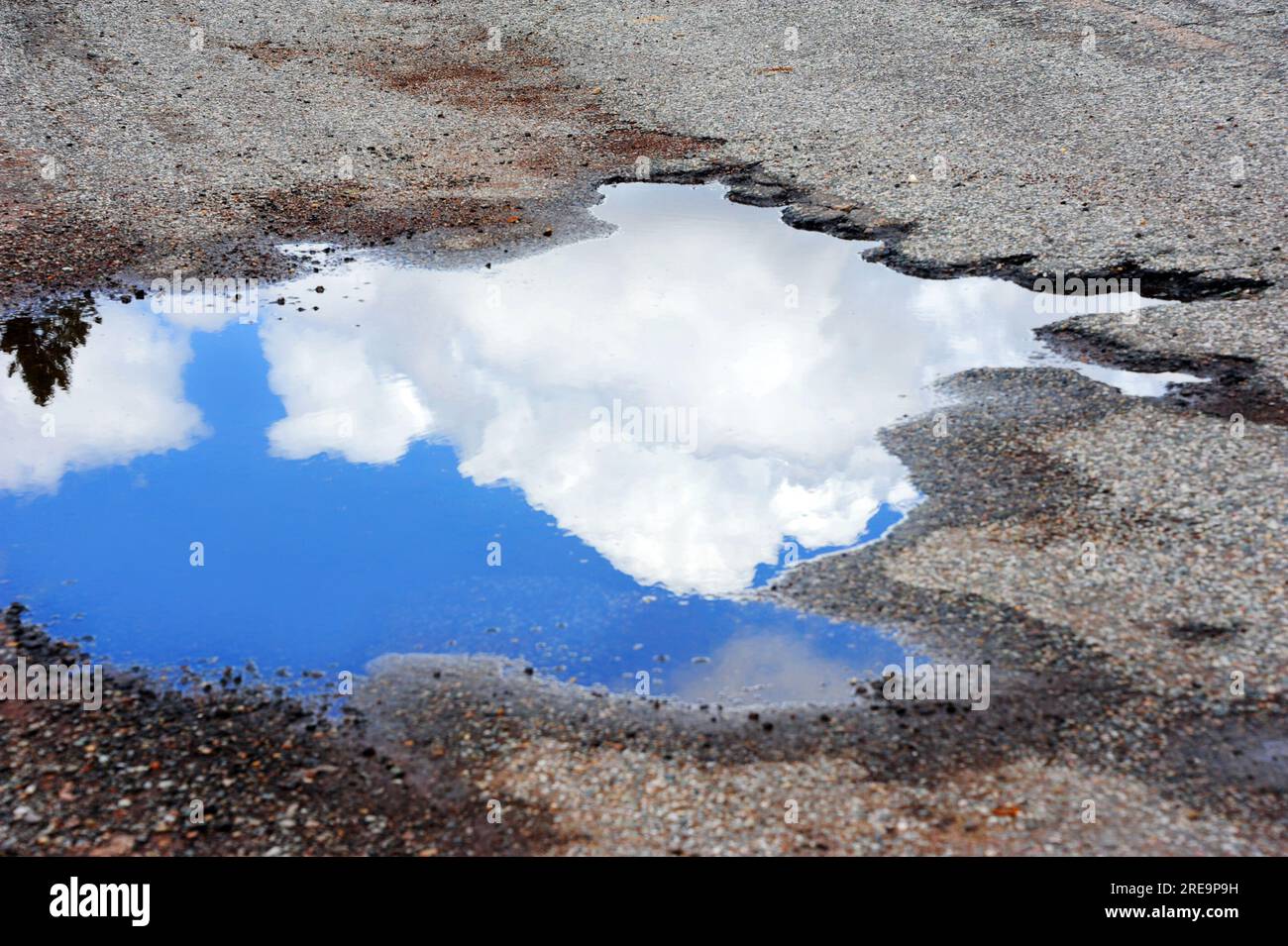 Ugly Pothole Is Beautiful With A Blue Sky Reflection And White Fluffy 