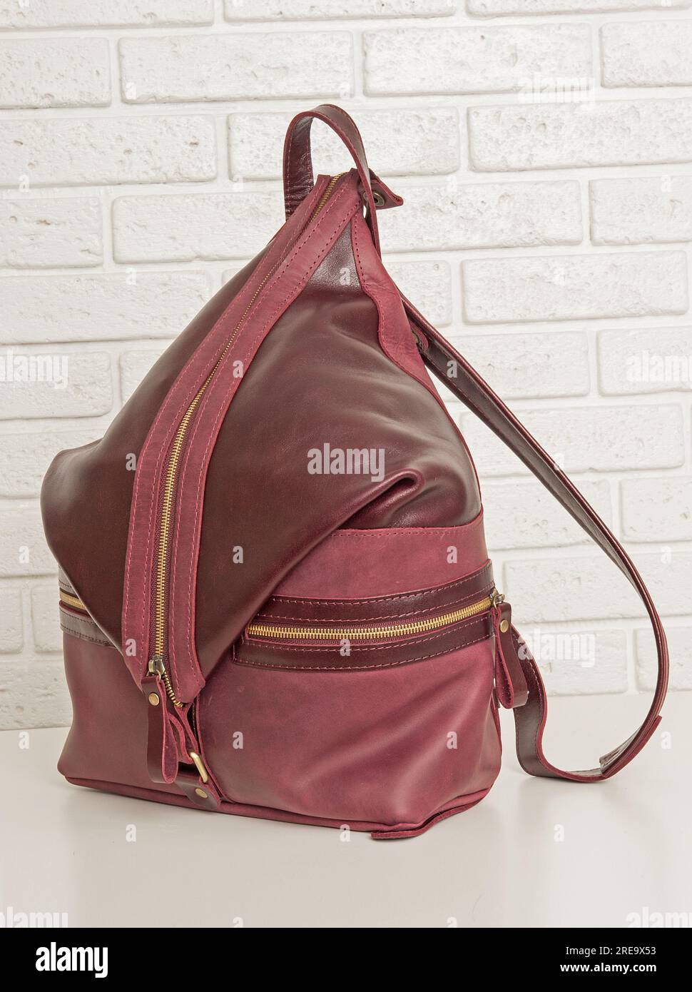 Brown leather backpack bag on white brick background Stock Photo