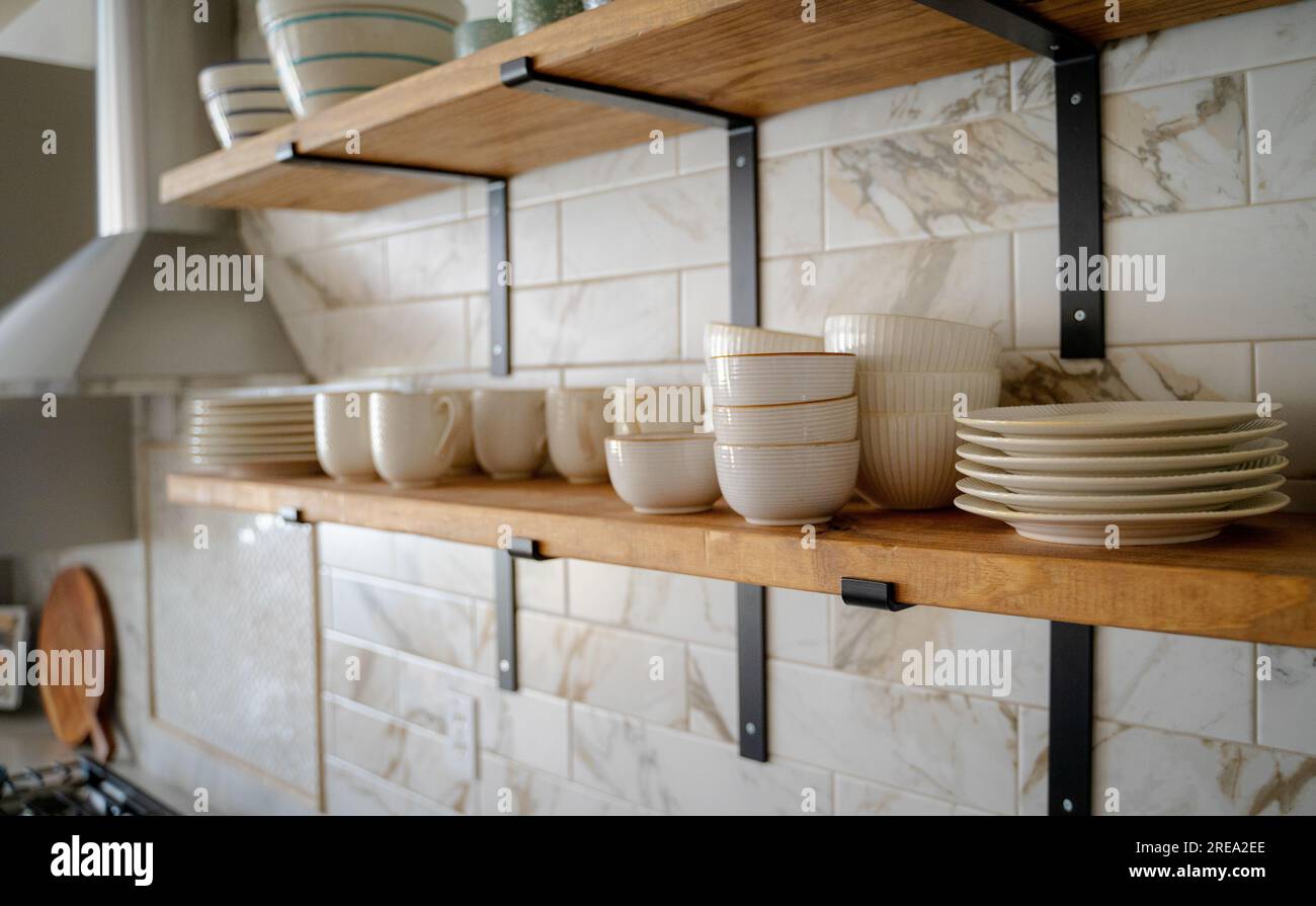 Open kitchen shelves with cups, plates and bowls Stock Photo