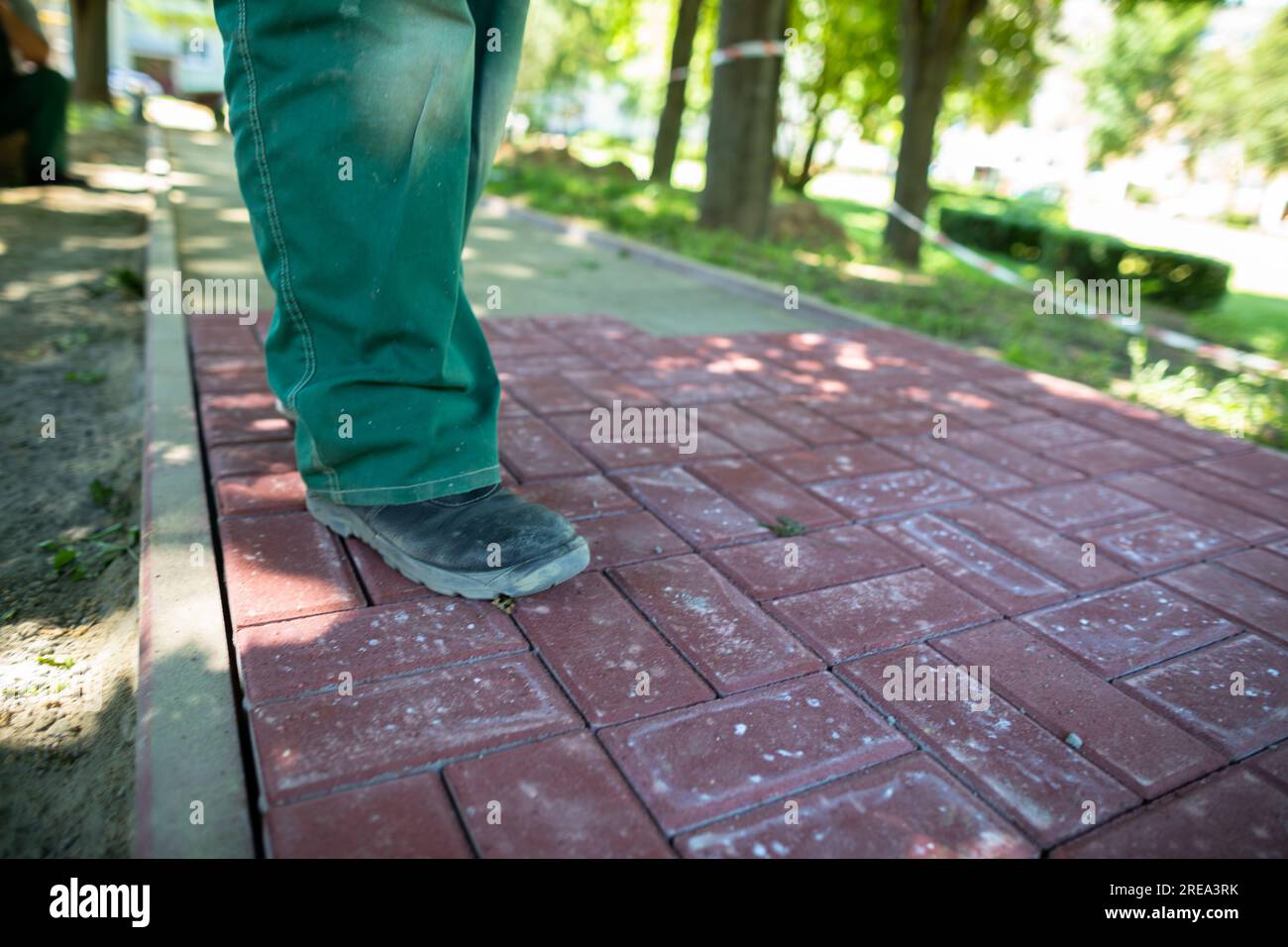 A worker in working clothes is standing on a cobblestone pavement. Stock Photo