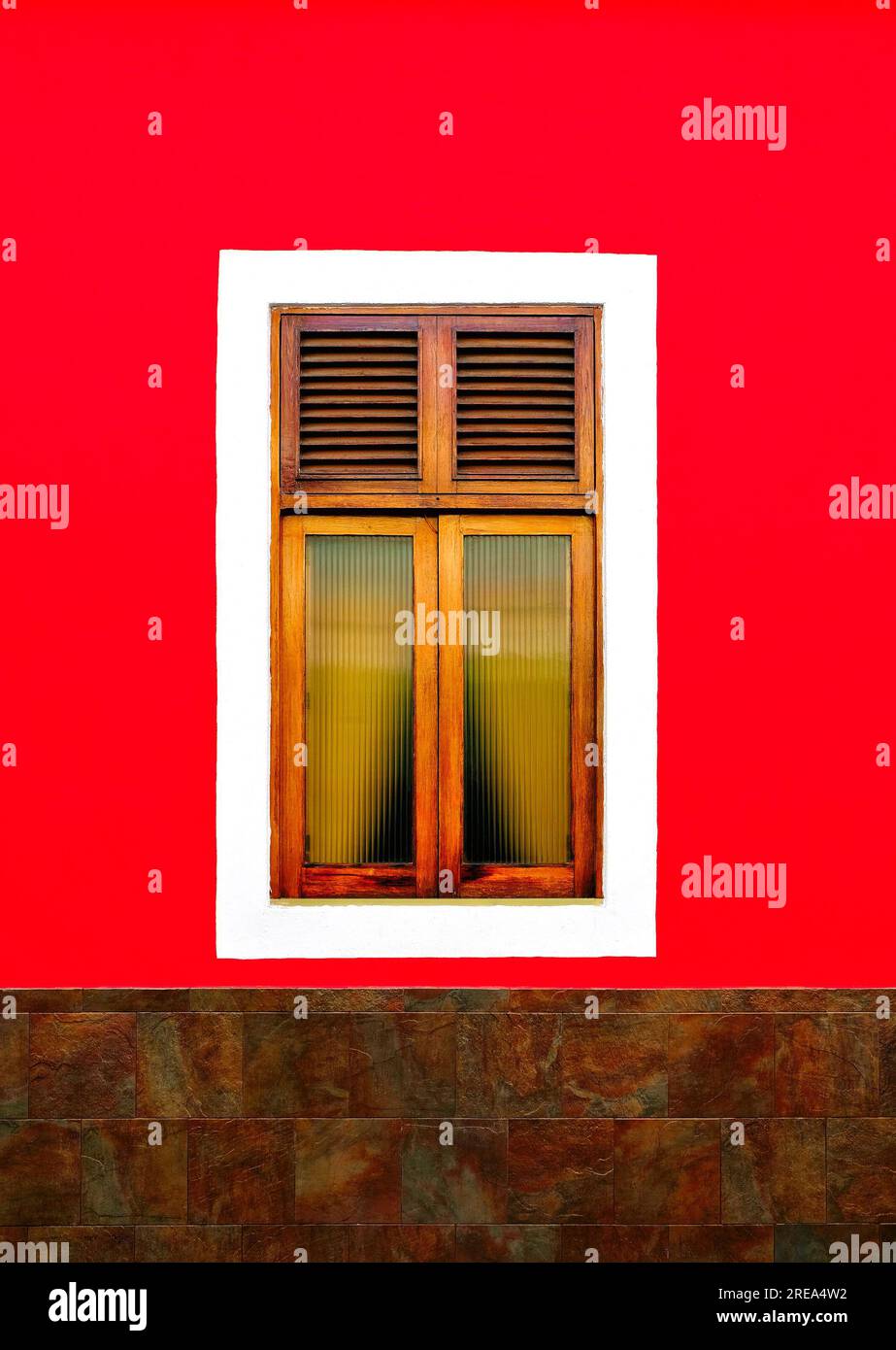 Simple classic wooden window in a bright red wall. Stock Photo