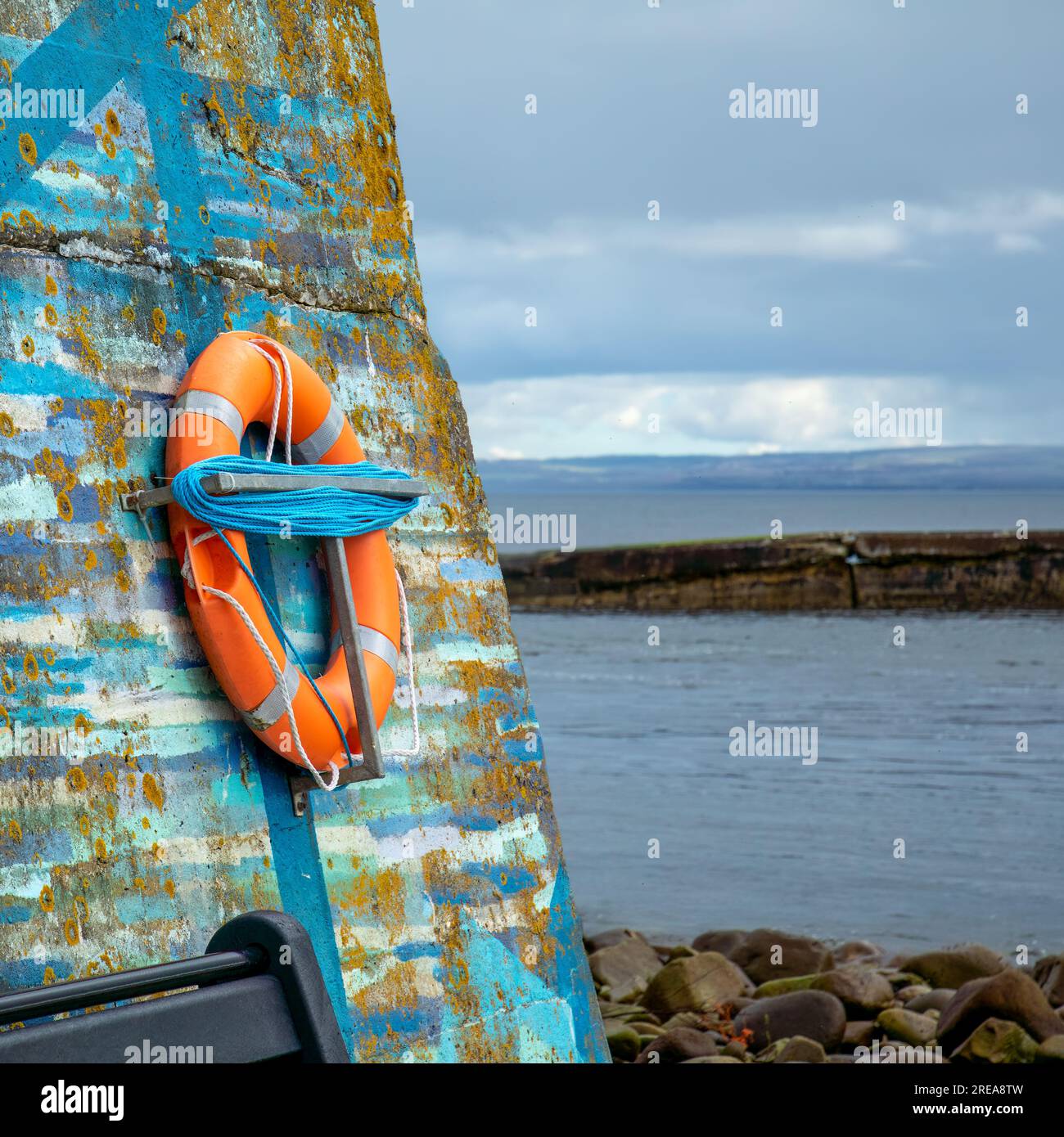 Safety life ring on a colourful wall by the water on the coast Stock Photo