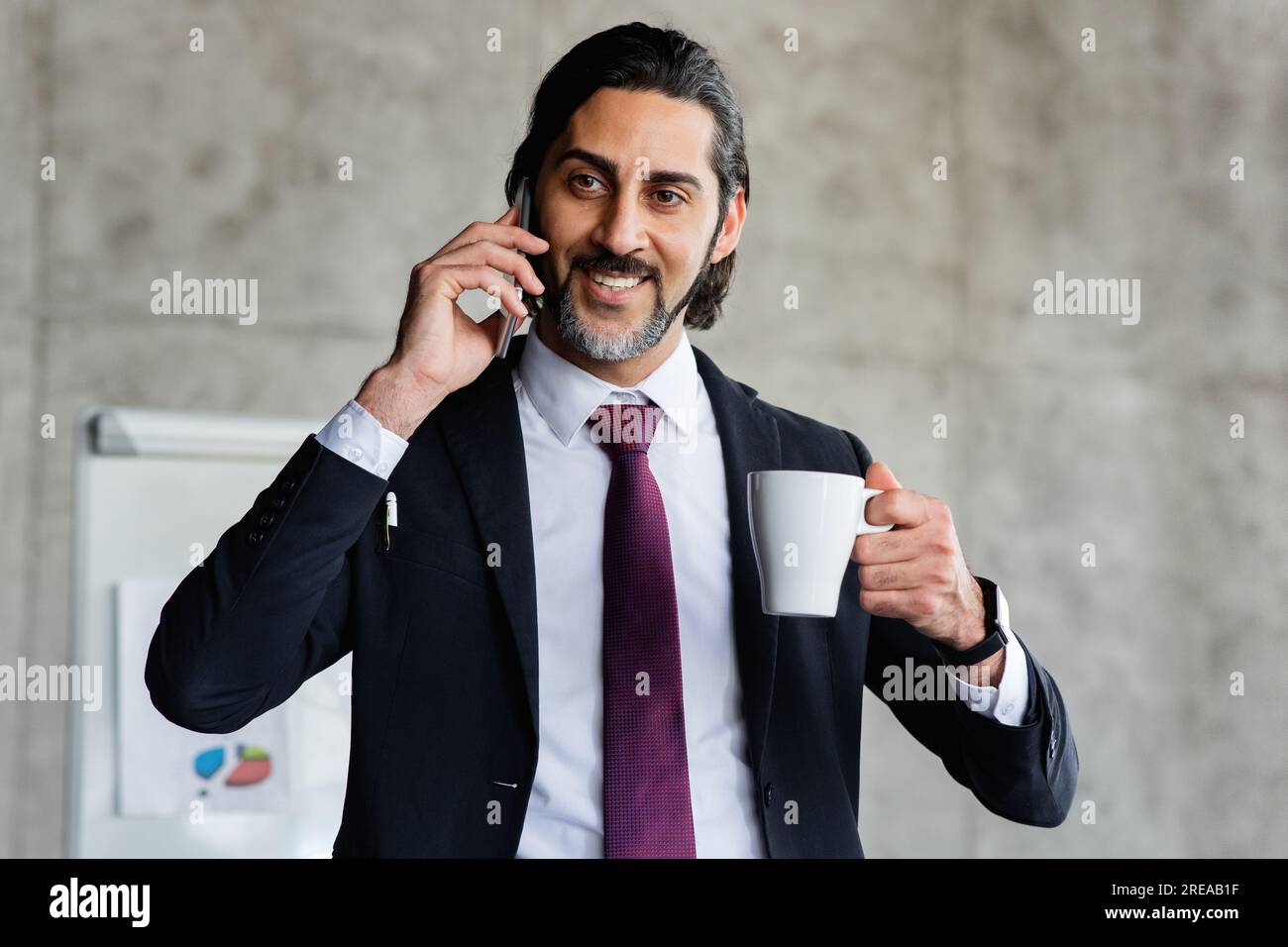 Cheerful attractive manager talking on phone, drinking coffee Stock Photo