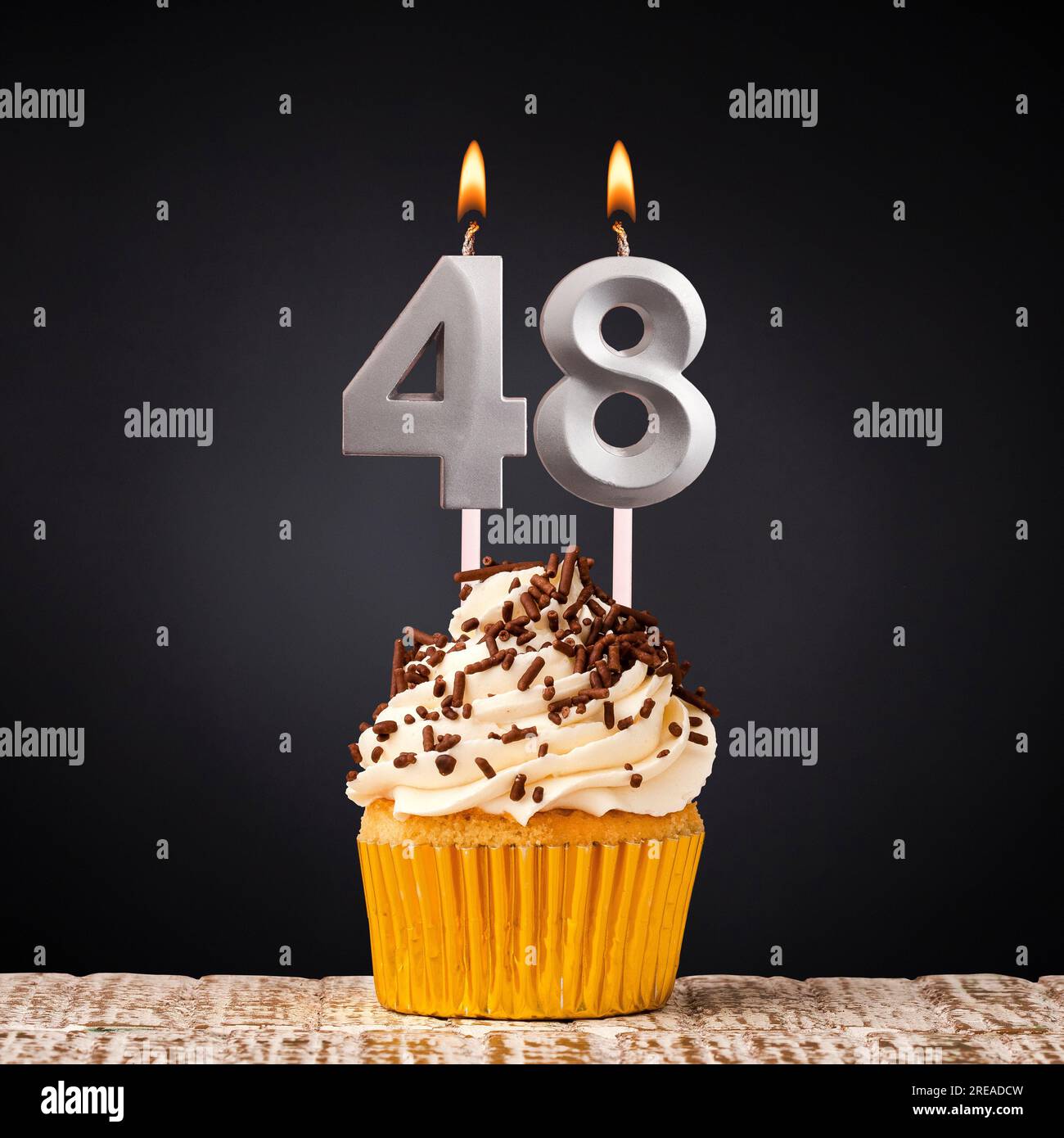 Cupcake with sparkling candle for 39th birthday or anniversary with big  number in white with yellow streamers on blue table with dark background  full Stock Photo - Alamy