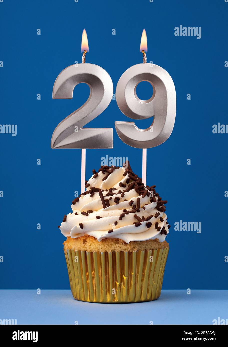 Burning candle number 29 - Birthday card with cake on blue Background Stock Photo
