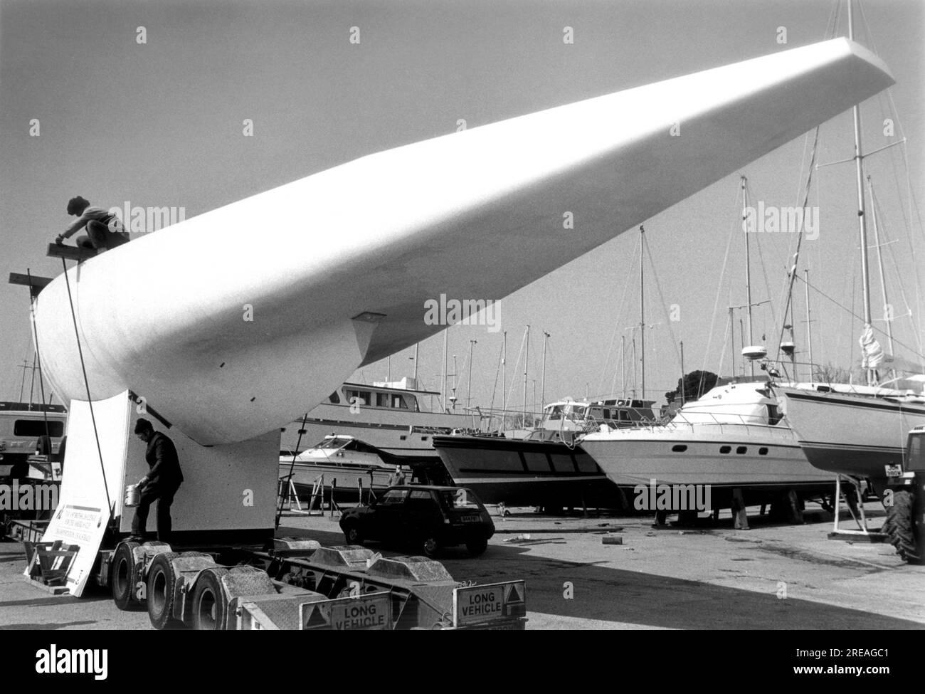 AJAXNETPHOTO. 1986. SWANWICK, ENGLAND. - AMERICA'S CUP 1986 -NEW BRITISH 12M 'THE HIPPO' (WHITE CRUSADER SAIL NR K-25) - DESIGNED BY DAVID HOLLOM ARRIVES AT A.H.MOODY'S YARD ON THE HAMBLE. PHOTO:JONATHAN EASTLAND/AJAX. REF:12M 1986 Stock Photo