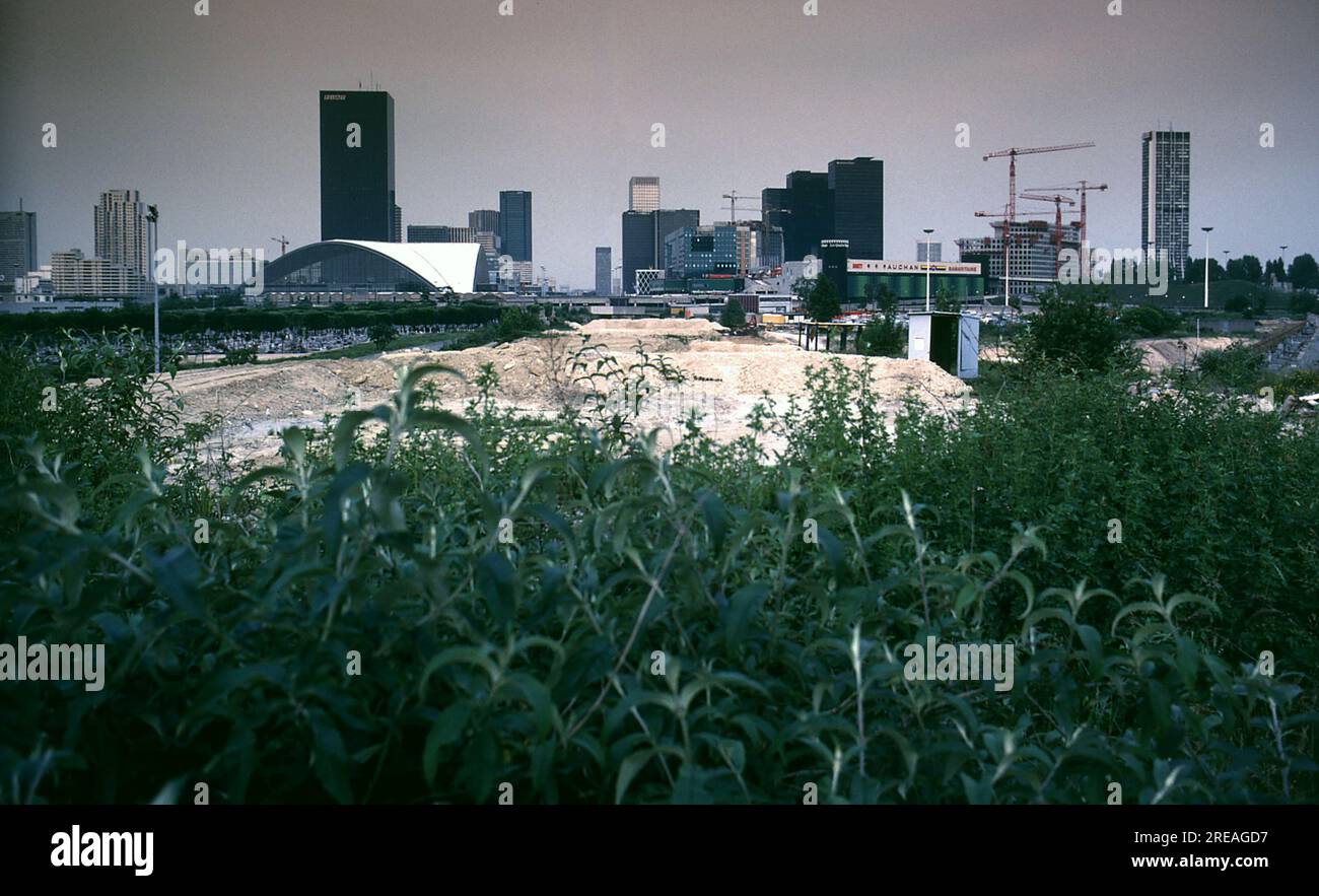 AJAXNETPHOTO. 2ND NOVEMBER, 1983. PARIS, NANTERRE, FRANCE - TAKING SHAPE - CONSTRUCTION ON-GOING IN THE BUSINESS DISTRICT OF LA DEFENSE. CENTRE IS THE AXIS ON WHICH THE LA DEFENSE 'GRANDE ARCHE' WILL ULTIMATELY BE BUILT WITH THE ARC DE TRIOMPHE IN CENTRAL PARIS STILL VISIBLE (CENTRE, DISTANT HORIZON.) IN THIS PICTURE. THE CEMETERY OF NEUILLY CAN BE SEEN LEFT. PHOTO:JONATHAN EASTLAND/AJAX REF: 842164 121 Stock Photo