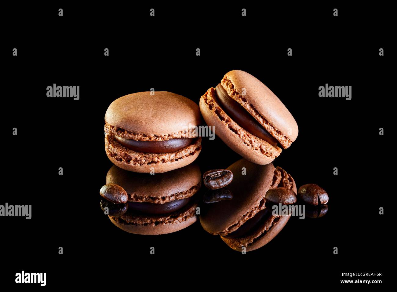 Flavoured coloured macarons on a reflective surface with coffee beans Stock Photo