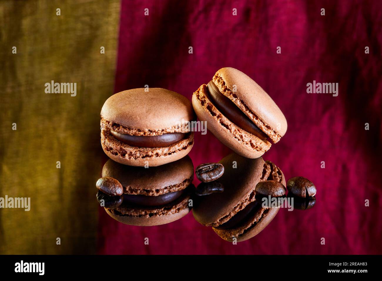 Flavoured coloured macarons on a reflective surface with coffee beans Stock Photo
