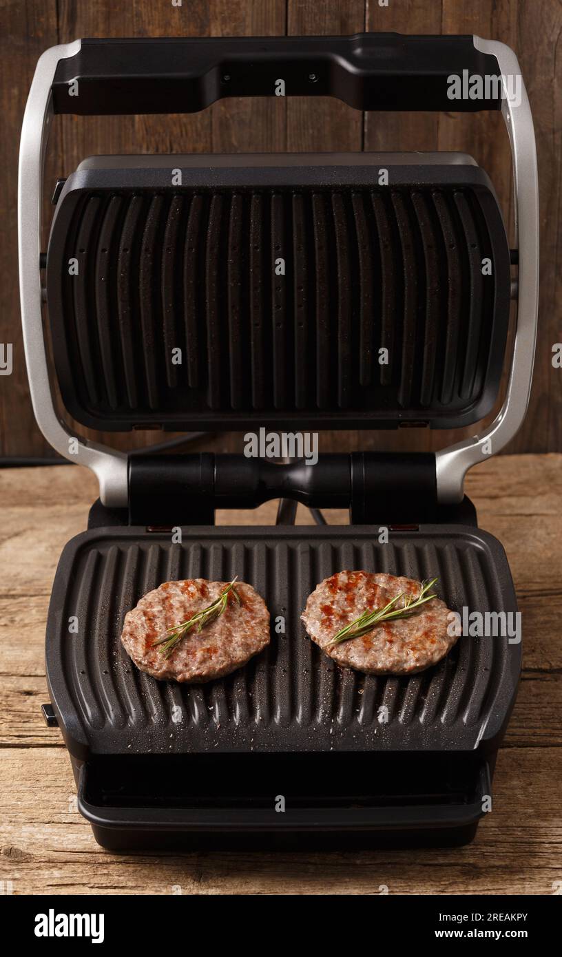 Beef patties for a burger are fried with spices on a smart electric grill. Cooking homemade
