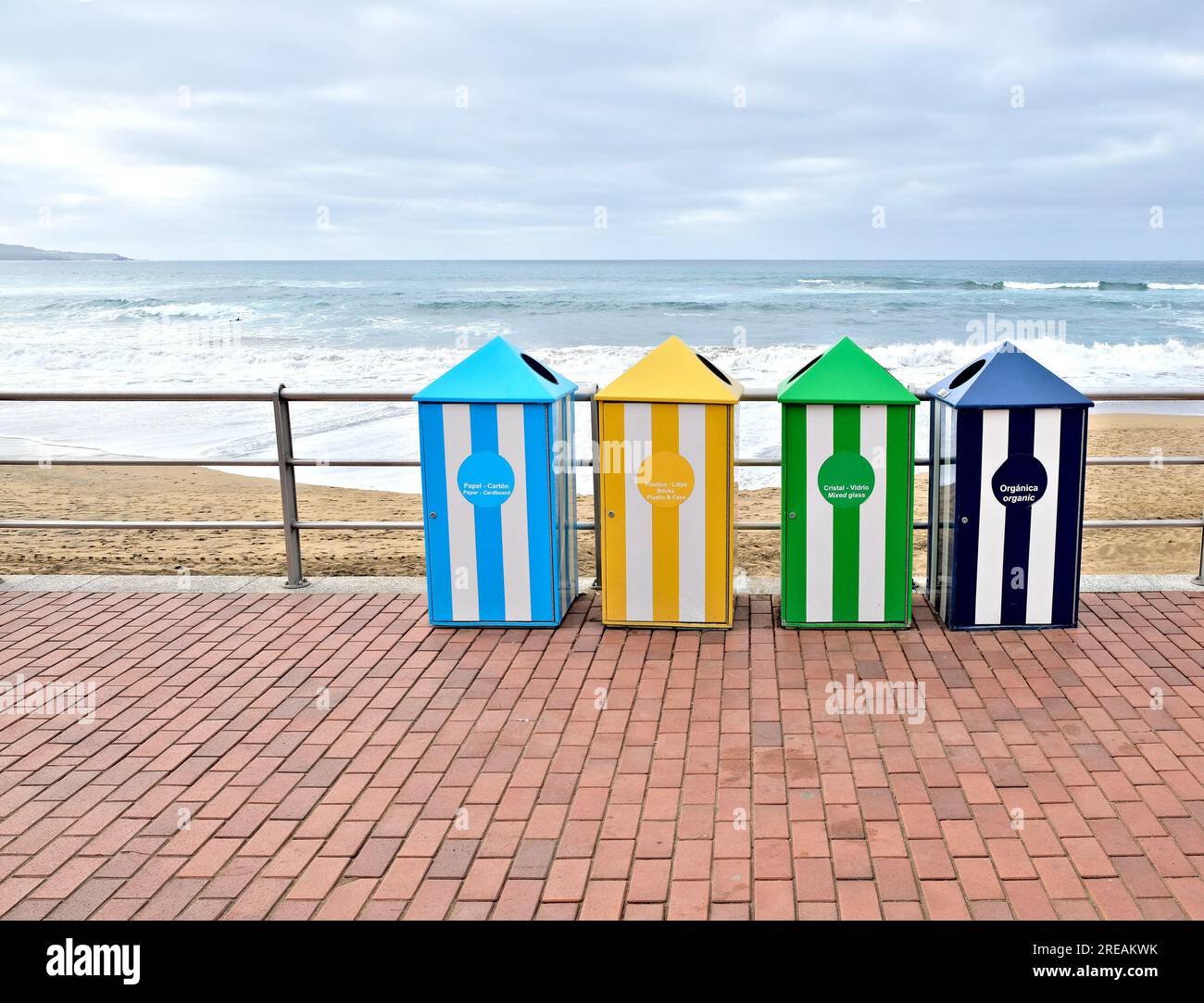 Colorful recycling bins at the beach, with waste management instructions in English and Spanish. Stock Photo