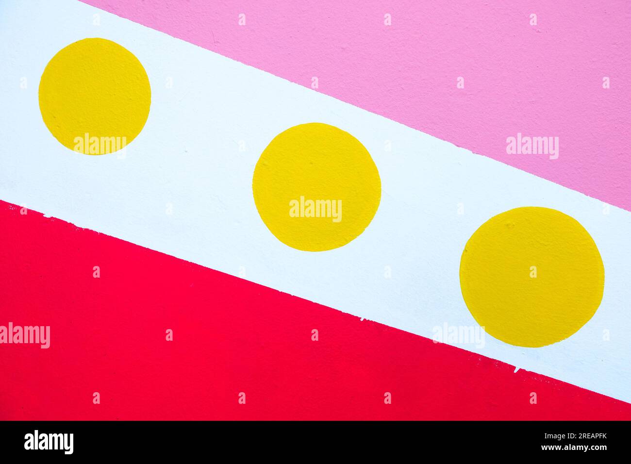 Three yellow dots on white background with pink and red patches Stock
