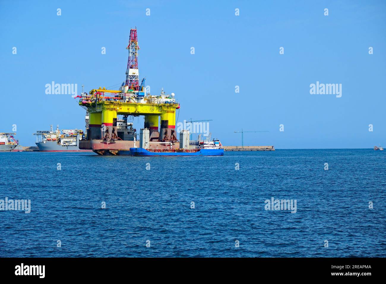 Huge crude oil rig equipment and a service ship on the water. Stock Photo