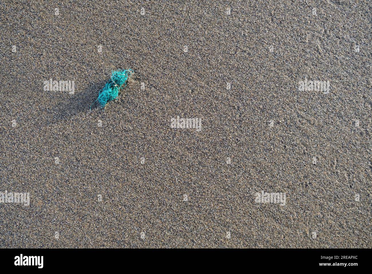 A small piece of plastic on a beach. Shoreside pollution concept. Stock Photo