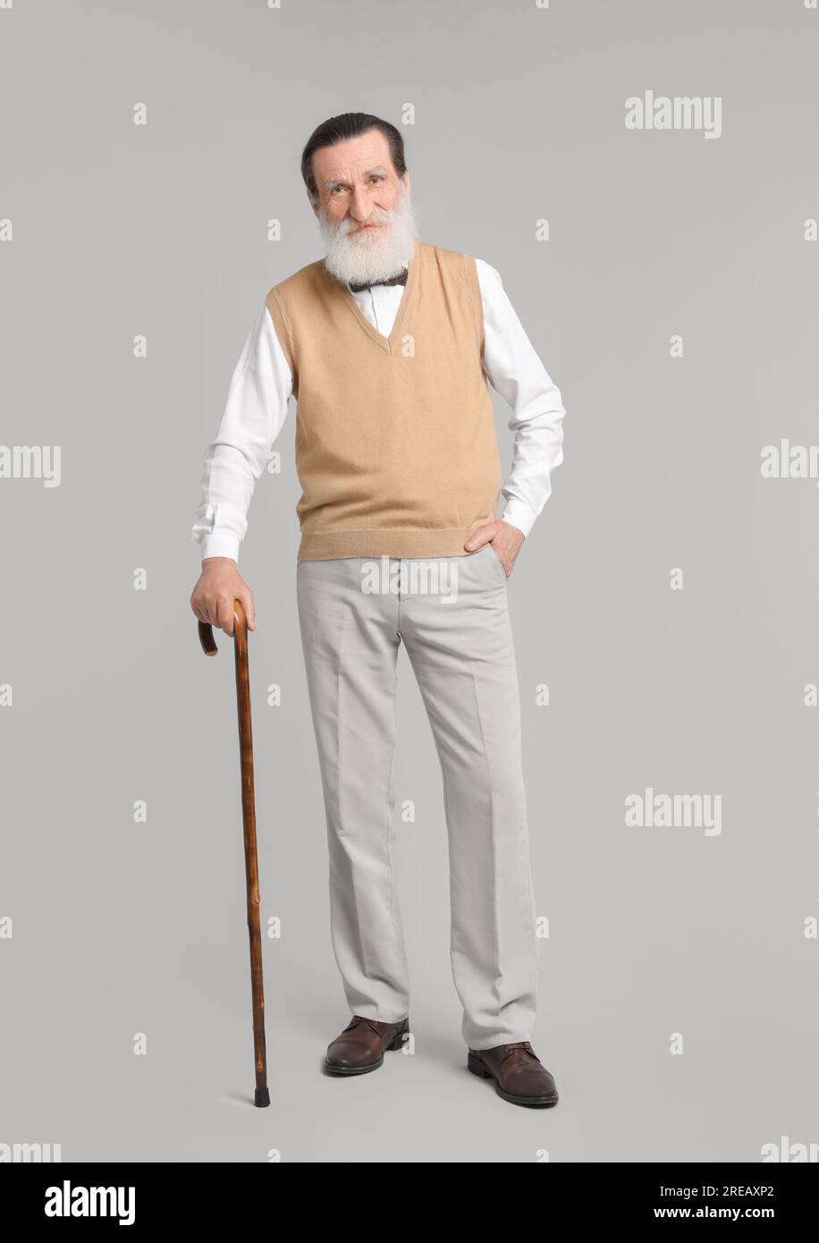 Senior man with walking cane on light gray background Stock Photo - Alamy