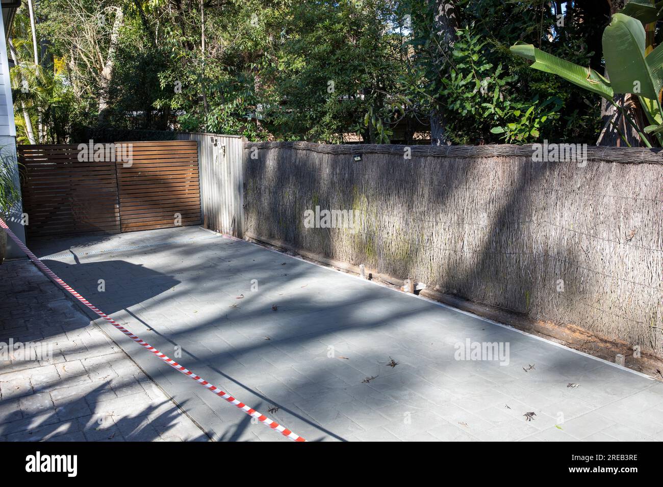 Australia, new concrete driveway poured at side of an Australian home in Sydney, concrete is drying and is taped off Stock Photo