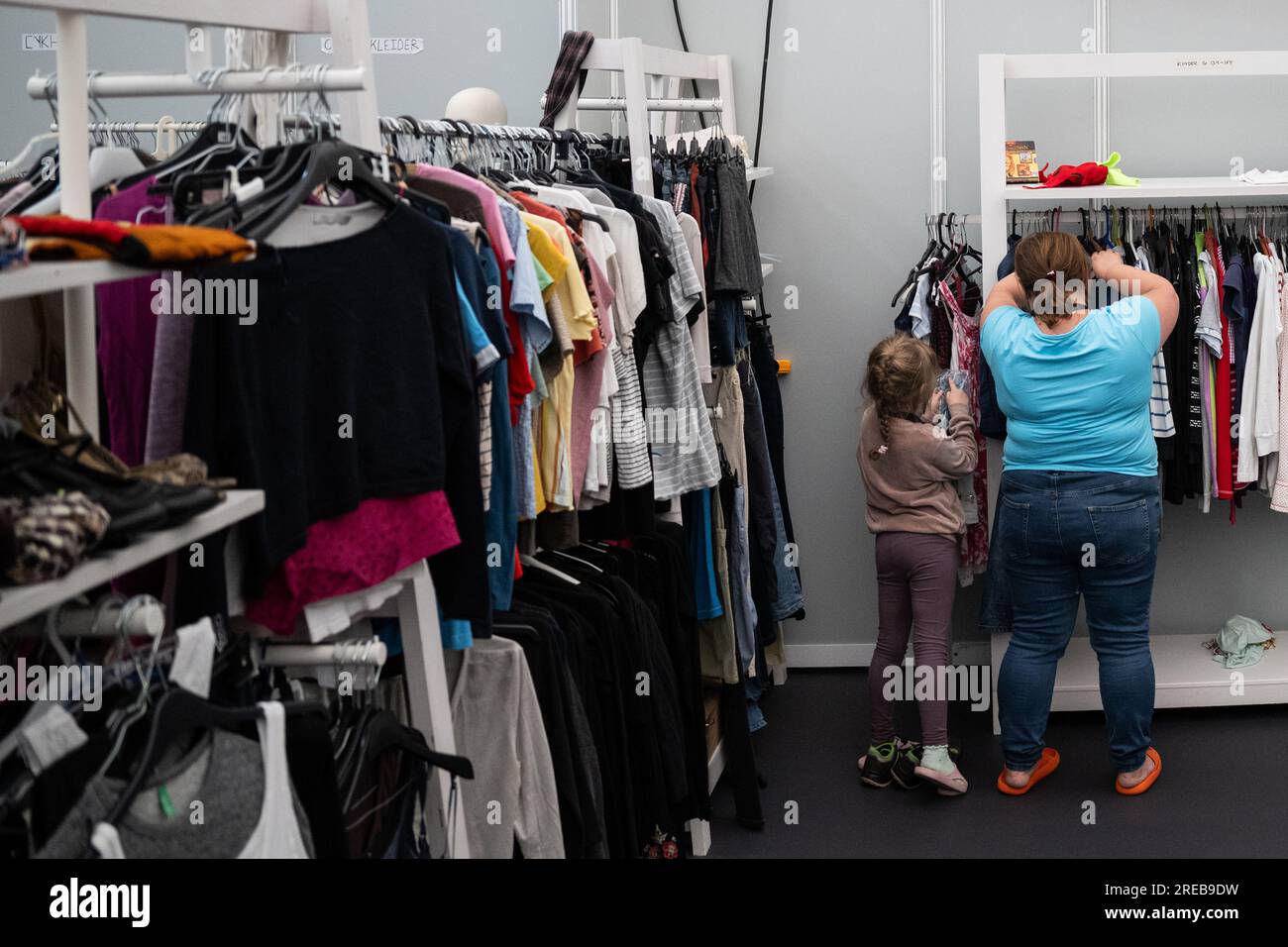 Berlin, Germany. 26th July, 2023. A woman and child pick out clothes in the  so-called boutique at the Tegel arrival center. The refugee accommodation  at the former Tegel Airport houses around 2,500