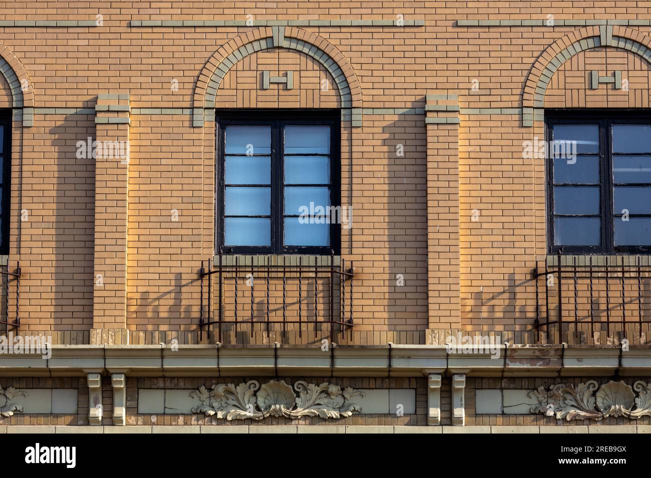 Full frame texture background of a beautiful beige color early 20th century American style brick wall facade with decorative arched window frames Stock Photo