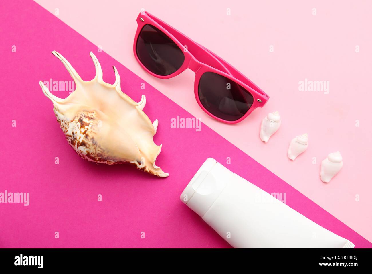 Composition with sunglasses, seashells and sunscreen on pink background Stock Photo