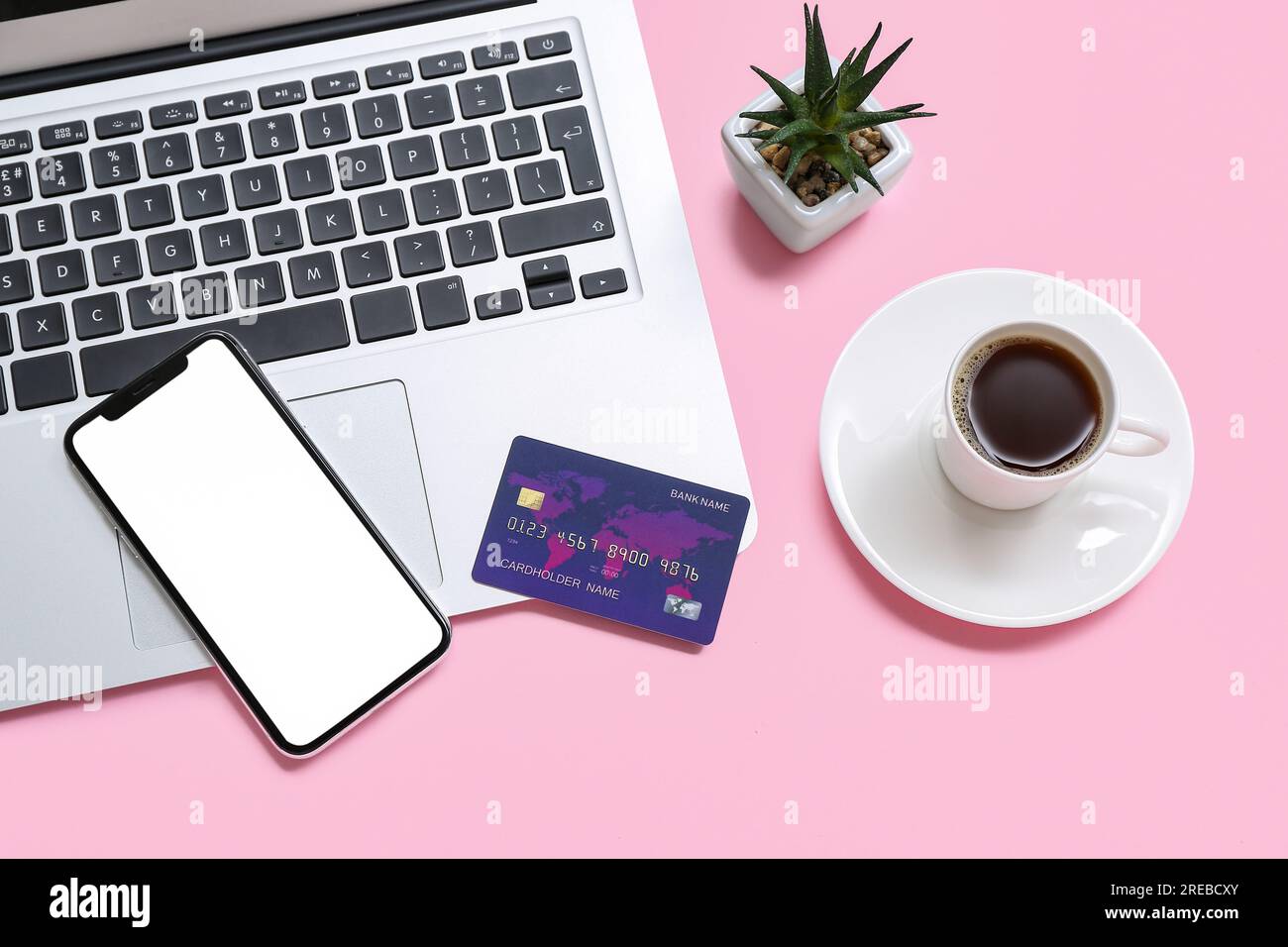 Laptop with credit card, cup of coffee and mobile phone on pink background Stock Photo