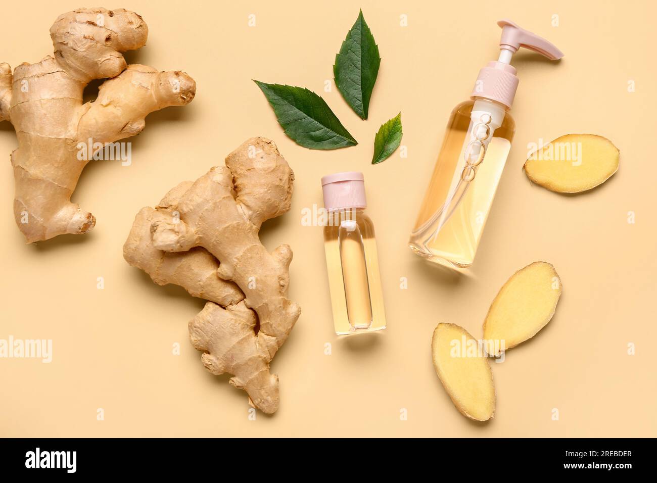 Bottles of ginger cosmetic oil and leaves on yellow background Stock