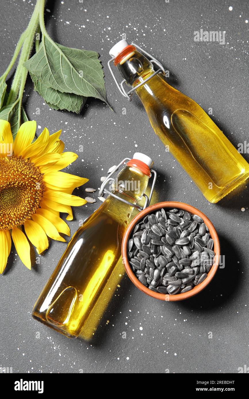 Bottles of sunflower oil and bowl with seeds on black background Stock ...