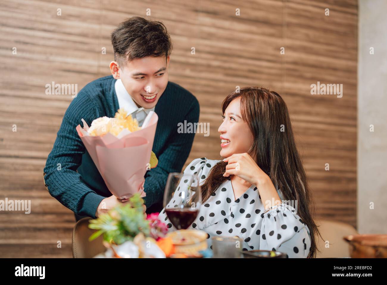 Young man greeting his girlfriend on Valentine's Day at restaurant Stock Photo